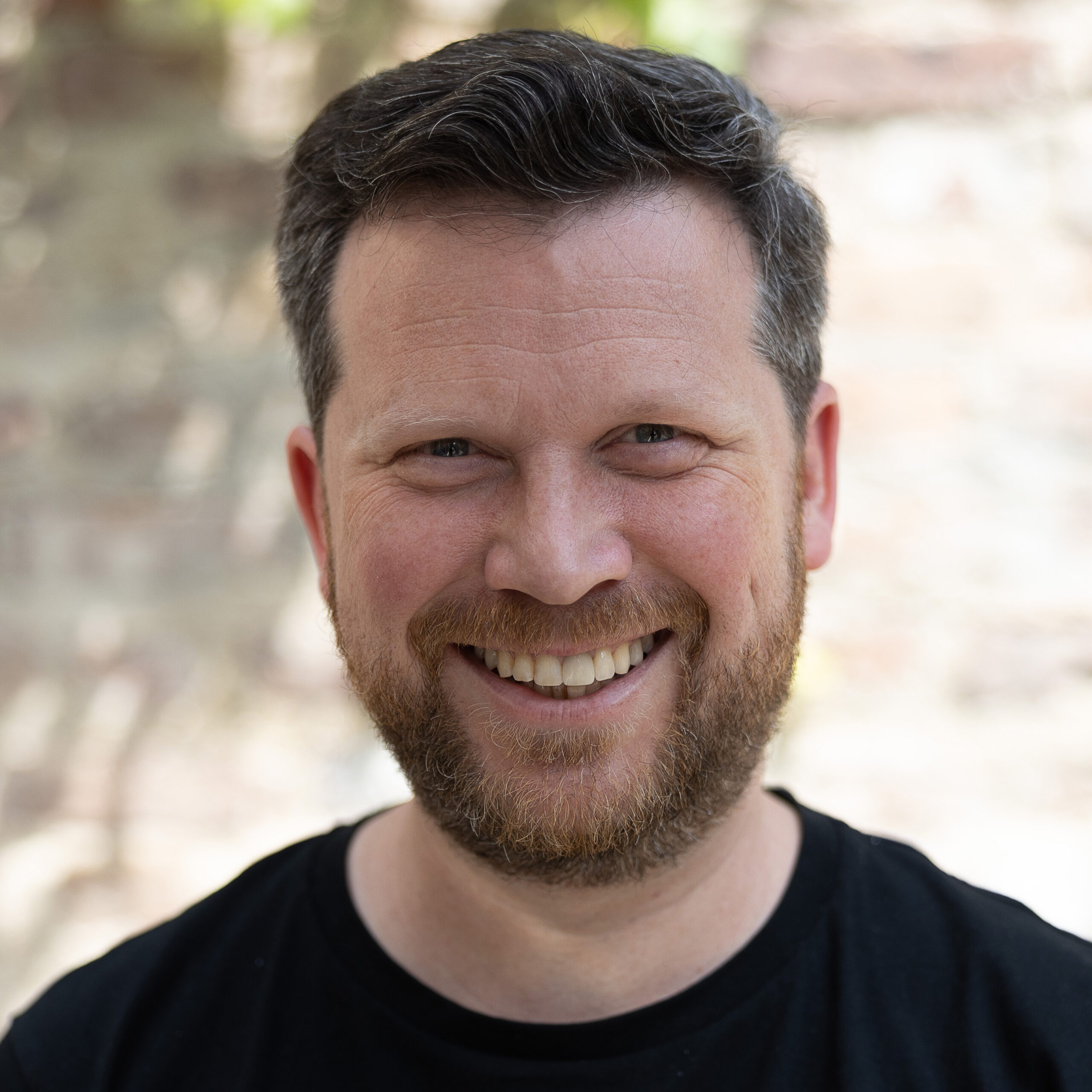 Ein lächelnder Mann mit Bart.